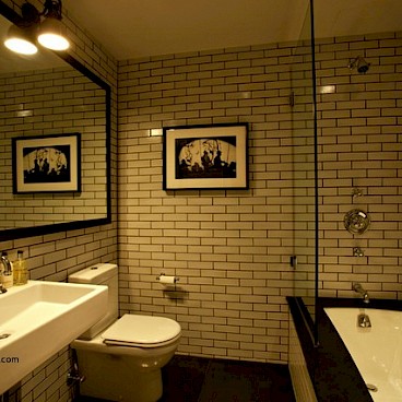 Лофт в этой маленькой ванной создают стены, картина, правильное освещение и зеркало